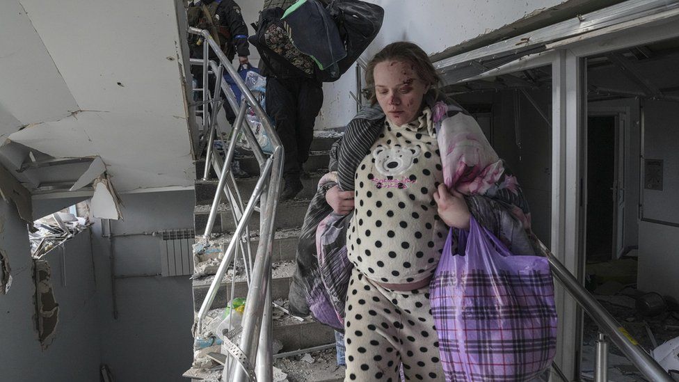 An injured pregnant woman walks downstairs in a maternity hospital damaged by shelling in Mariupol, Ukraine, Wednesday, March 9, 2022