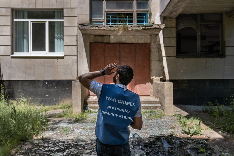 A Kharkiv regional prosecutor inspects shell damage at an agricultural college near the city. Prosecutors have had to learn quickly how to conduct war crimes investigations.