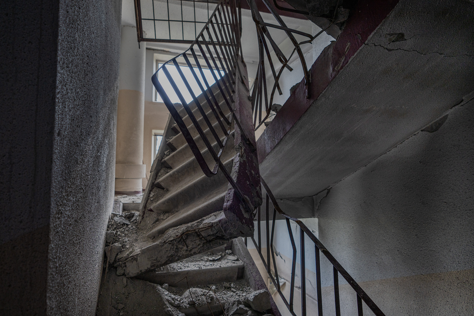 The concrete stairwell two floors above Roman's apartment, smashed by a direct hit on the roof