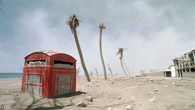 A red phone box is buried in volcanic ash and sand after eruptions on the Caribbean island of Montserrat
