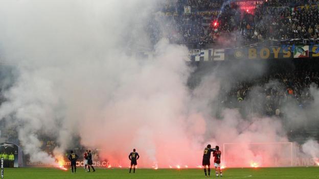 Rui Costa and Marco Materazzi watch as flares fall on the pitch at the San Siro during AC Milan and Inter's 2005 Champions League quarter-final