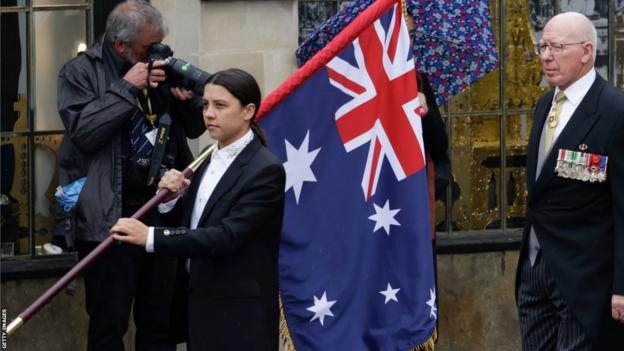 Sam Kerr leads the Australian delegation at King Charles' coronation, carrying a large Australian flag