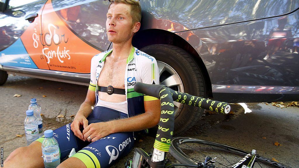 Christian Meier leans against a car, with his bike on the ground next to him, after riding in the Tour de France