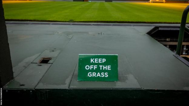 Centre Court in the background of a sign saying Keep Off the Grass