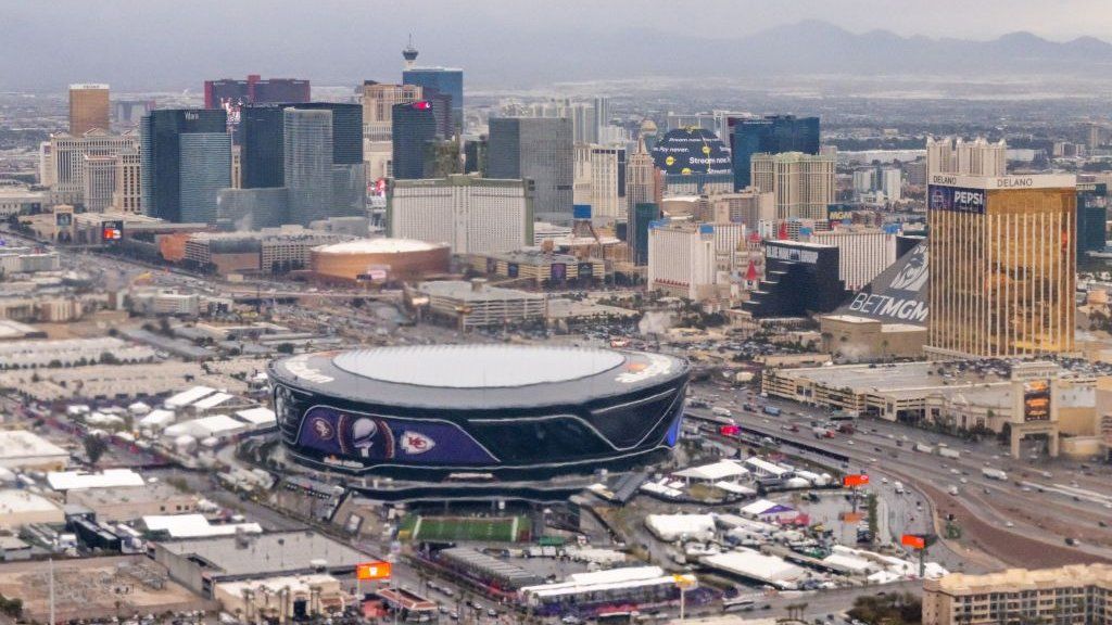 The Allegiant Stadium seen from above with the Las Vegas skyline beyond