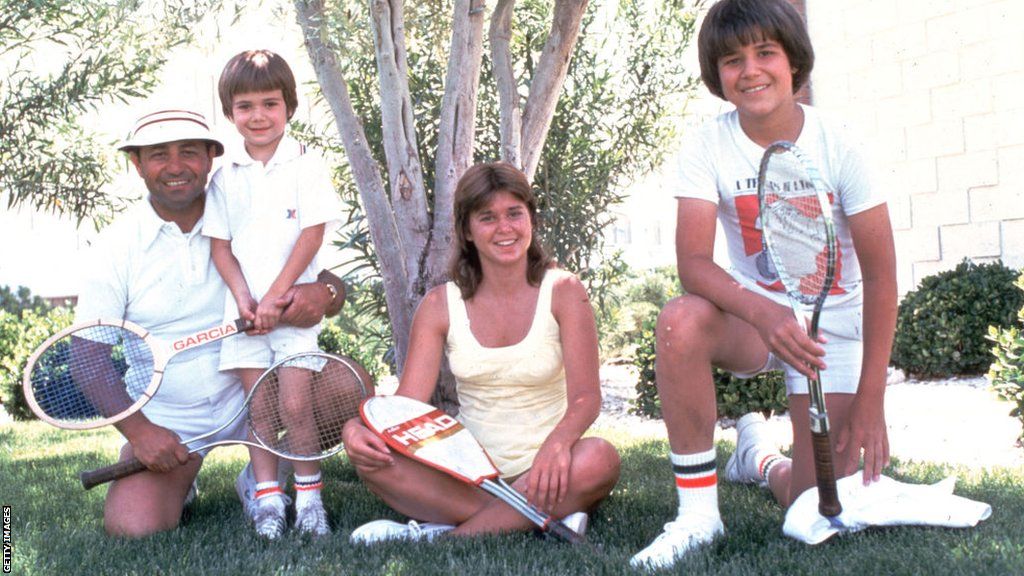 The Agassi family, with a young Andre, pose in front of a tree while holding tennis racquets
